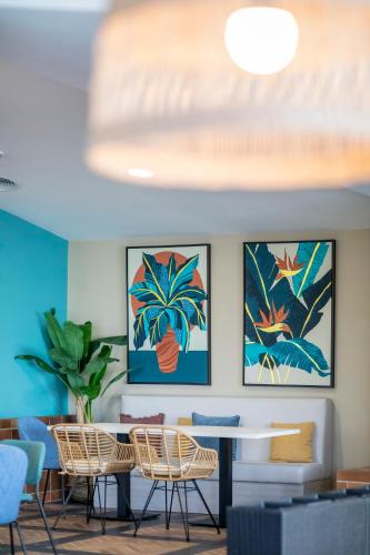 a room with chairs and a table with paintings on the wall at Soho Boutique Puerto in El Puerto de Santa María