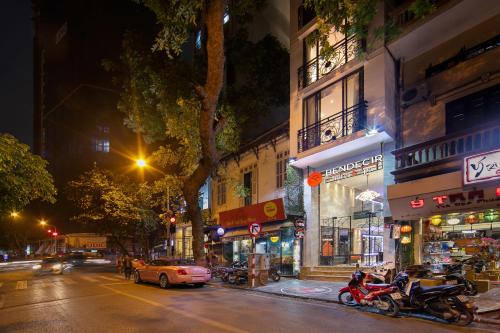 a city street at night with motorcycles parked on the street at Bendecir Hotel & Spa in Hanoi
