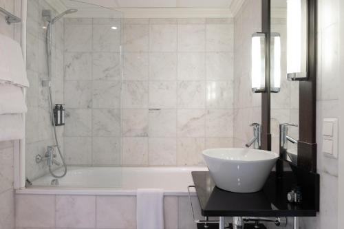 a white bathroom with a tub and a sink at Elite Palace Hotel & Spa in Stockholm
