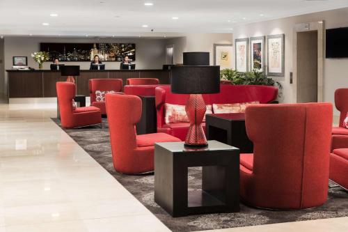 a waiting room with red chairs and a lamp at Rydges World Square in Sydney