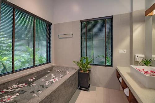 a bathroom with a tub and a sink and windows at Grange in Siem Reap