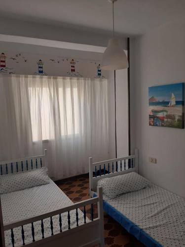 two twin beds in a room with a window at Las Palmeras 1 in Águilas