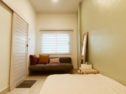 a bedroom with a bed and a couch in front of a window at Sundae Haus in Betong