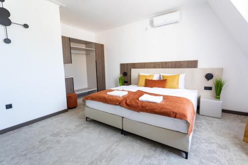 a bedroom with a large bed with orange blankets and pillows at Laguna Panzió in Gárdony