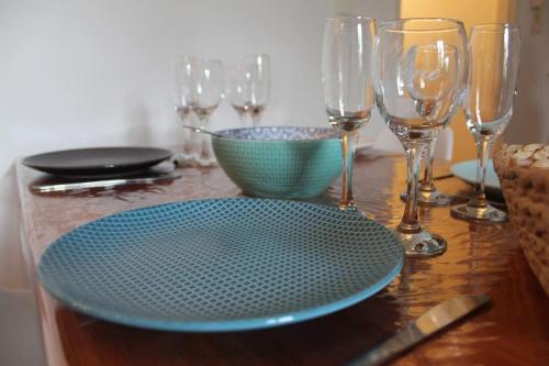 uma mesa de madeira com um prato azul e copos de vinho em Appartement calme proche de la Loire em Saumur