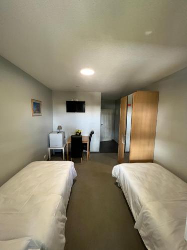 a room with two beds and a table with a chair at Motel am Outletcenter in Neumünster