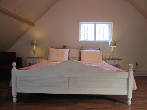 um quarto com uma cama branca com almofadas e uma janela em B&B Boerderij Wijtvliet em Langeweg