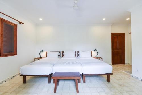 a bedroom with four beds with white sheets at Oh Battambang Boutique Hotel in Battambang