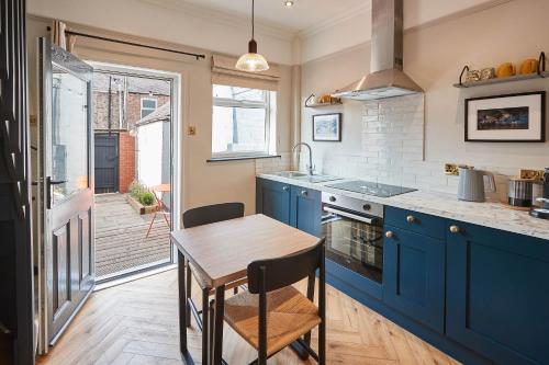 a kitchen with blue cabinets and a wooden table at Host & Stay - The Railman's House in York