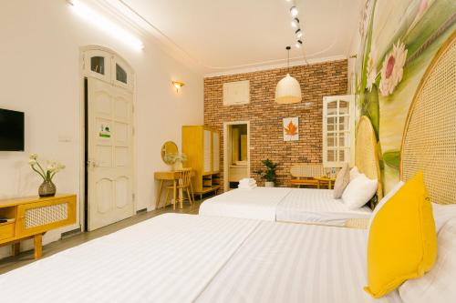 a bedroom with two beds and a brick wall at Eden Westlake Hotel in Hanoi