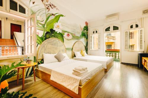 a bedroom with two beds and a mural of flowers at Eden Westlake Hotel in Hanoi