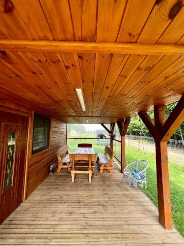 a wooden deck with a table and chairs on it at DOMEK LETNISKOWY POD BRZOZAMI na Roztoczu wśród lasów, Zamość, Krasnobród, Zwierzyniec in AdamÃ³w