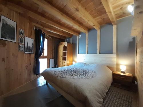 FontrabiouseにあるMaison de montagne dans charmant village du Capcirの木製の壁のベッドルーム1室(大型ベッド1台付)