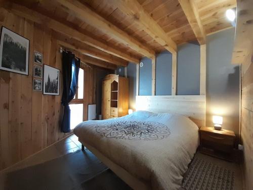 une chambre avec un grand lit dans une pièce aux murs en bois dans l'établissement Maison de montagne dans charmant village du Capcir, à Fontrabiouse