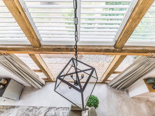 a chandelier hanging from the ceiling in a room with wooden ceilings at Pass the Keys Peaceful And Beautiful Barn In Downland Village in Chichester