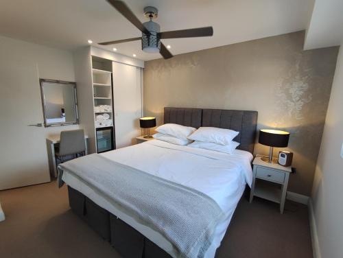 a bedroom with a large white bed with a ceiling fan at Modern 2 Bedroom Flat with private outdoor terrace in London