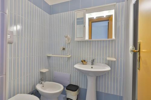 a bathroom with a sink and a toilet and a mirror at Villaggio Selene Mare in Paestum