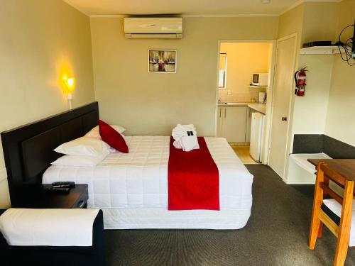 a hotel room with a bed and a kitchen at Monument Motor Lodge Papakura in Auckland