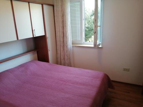ロヴィニにあるApartman Morenoのベッドルーム(紫色のベッド1台、窓付)