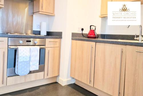 a kitchen with wooden cabinets and a red telephone at Contractors 2Bedrooms Apartment with Balcony & Free Parking by White Orchid Property Relocation in Stevenage