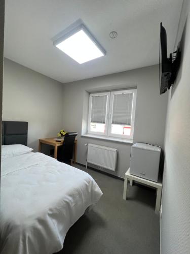 a bedroom with a bed and a desk and a window at Motel am Outletcenter in Neumünster