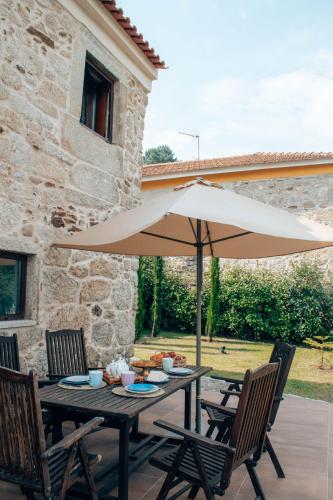 a table with an umbrella in front of a building at Just Like Home - Holly House em Cerveira in Linhares