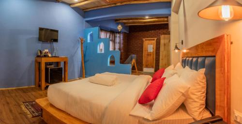 een slaapkamer met een groot wit bed met rode kussens bij Black Sheep Bed & Breakfast in Kargil
