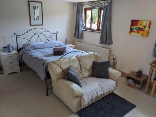 a bedroom with a bed and a couch and a chair at South Barn in Stanningfield