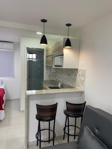 a kitchen with two bar stools and a counter at Flats Sol e Mar in São José da Coroa Grande