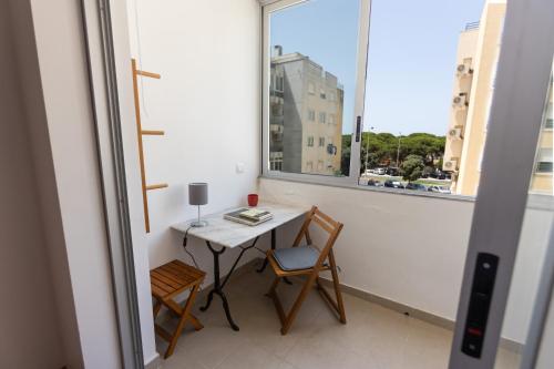 a small table and chairs in a balcony with a window at Sun & Beach Apartment by Soulplaces in Costa da Caparica