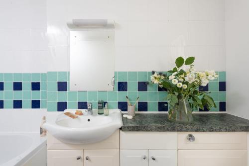 a bathroom with a sink and a vase of flowers at Rosebud in Portreath