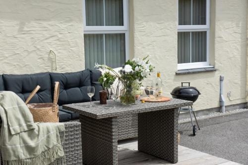 a patio with a table with flowers and a couch at Rosebud in Portreath