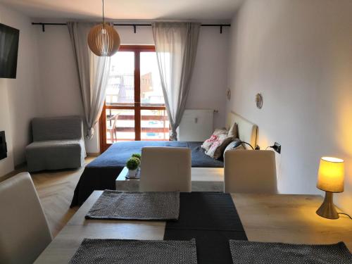 ein Wohnzimmer mit einem Bett, einem Tisch und Stühlen in der Unterkunft Ski&Bike Apartment Passo Tonale in Ponte di Legno
