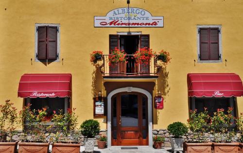 ComanoにあるAlbergo Miramontiの黄色の建物(ドア、バルコニー付)