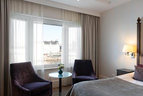 a hotel room with two chairs and a bed and a window at Elite Hotel Marina Plaza in Helsingborg