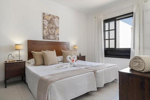 a white bedroom with a large bed and a window at Casa Marina 14 in Puerto del Carmen