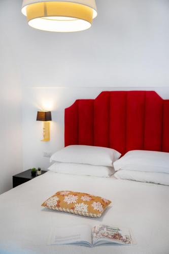 a bed with a red headboard and a book on it at Villa Mimina - Exclusive villa with garden, Jacuzzi and sea view in Praiano