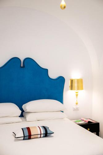 a bed with a blue headboard and a pillow on it at Villa Mimina - Exclusive villa with garden, Jacuzzi and sea view in Praiano