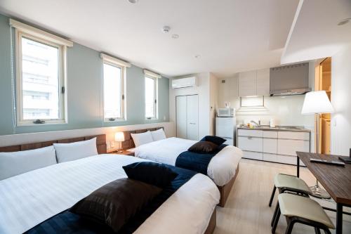 Cet appartement comprend une chambre avec deux lits, une table et une cuisine. dans l'établissement T・Kスクエア鹿児島中央, à Kagoshima