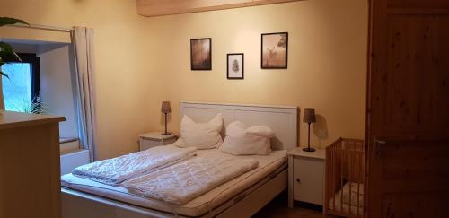 una camera da letto con letto, lenzuola e cuscini bianchi di Neumühle a Lutzerath