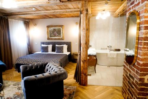 a bedroom with a bed and a bathroom with a tub at Boutique Hotel Virkas muiža in Kuldīga