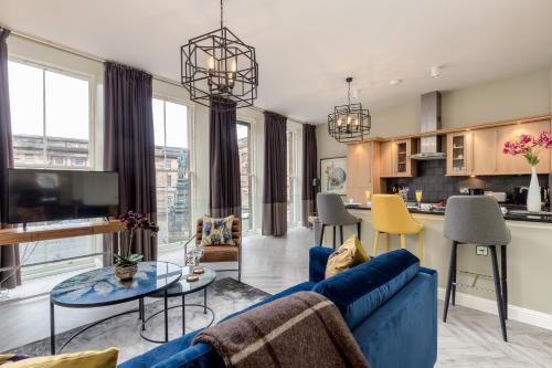 ein Wohnzimmer mit einem blauen Sofa und einer Küche in der Unterkunft JOIVY Luxury flats in Old Town, right on Royal Mile in Edinburgh