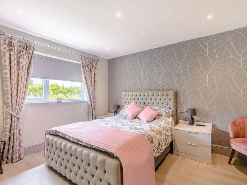 a bedroom with a bed with pink pillows and a window at Willows Cottage in Blackburn