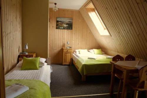 ein Schlafzimmer mit zwei Betten und einem Tisch und einem Fenster in der Unterkunft Pokoje Gościnne Staszelówka in Małe Ciche