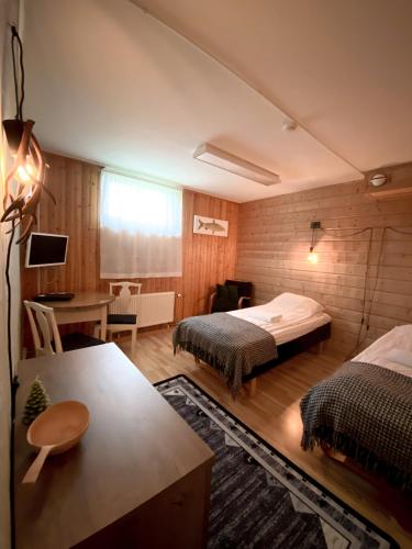 a hotel room with two beds and a desk at Lumi Guest House in Arvidsjaur