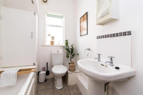 a white bathroom with a sink and a toilet at Characterful 2 bed apartment - Spacious & Comfy in Castle Donington