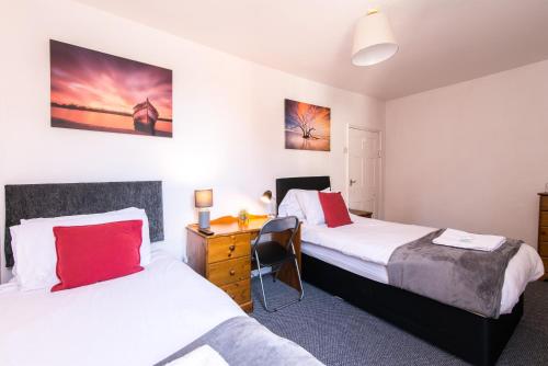 a bedroom with two beds and a desk with a chair at 2Bed Contractor Flat - East Midlands Airport - Castle Donington central in Castle Donington