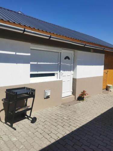 a grill in front of a building with a garage at Edit Vendégház in Tiszaújváros