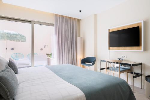 a hotel room with a bed and a television at El Vicenç de la Mar - Adults Only - Over 12 in Pollença