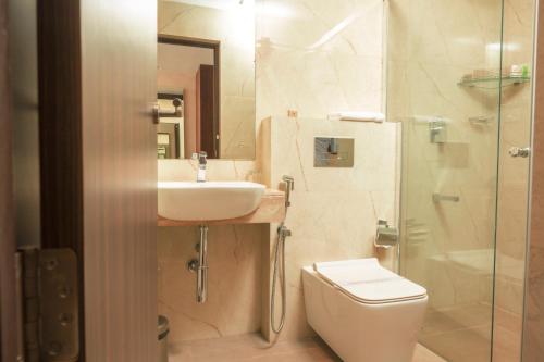 uma casa de banho com um WC, um lavatório e um chuveiro em THE RUNWAY HOTEL em Cochin